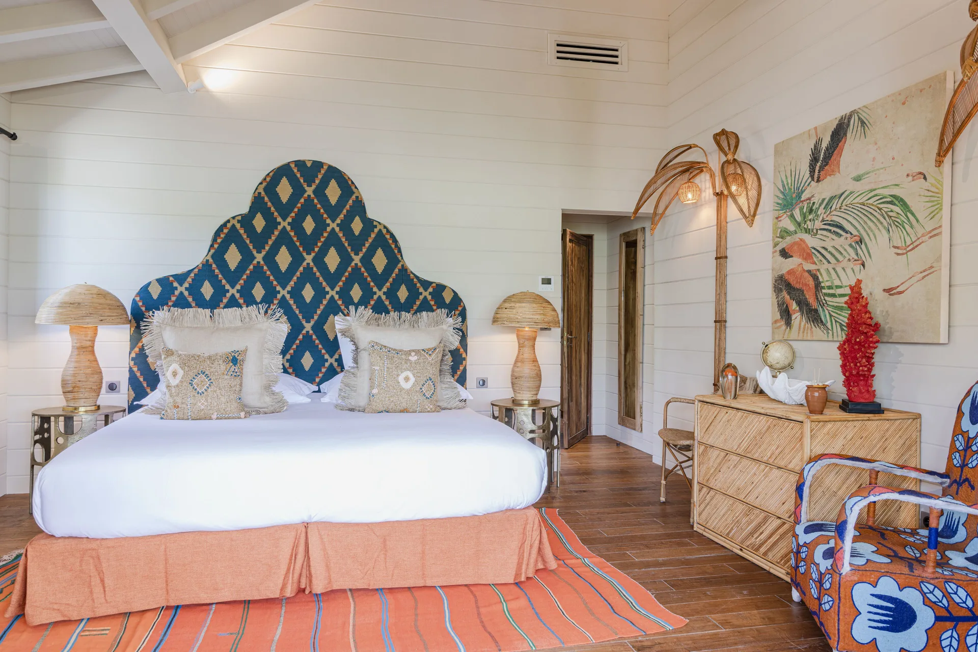 Guest bedroom with blue patterned headboard and lounge chair at GYP SEA Saint Barth.