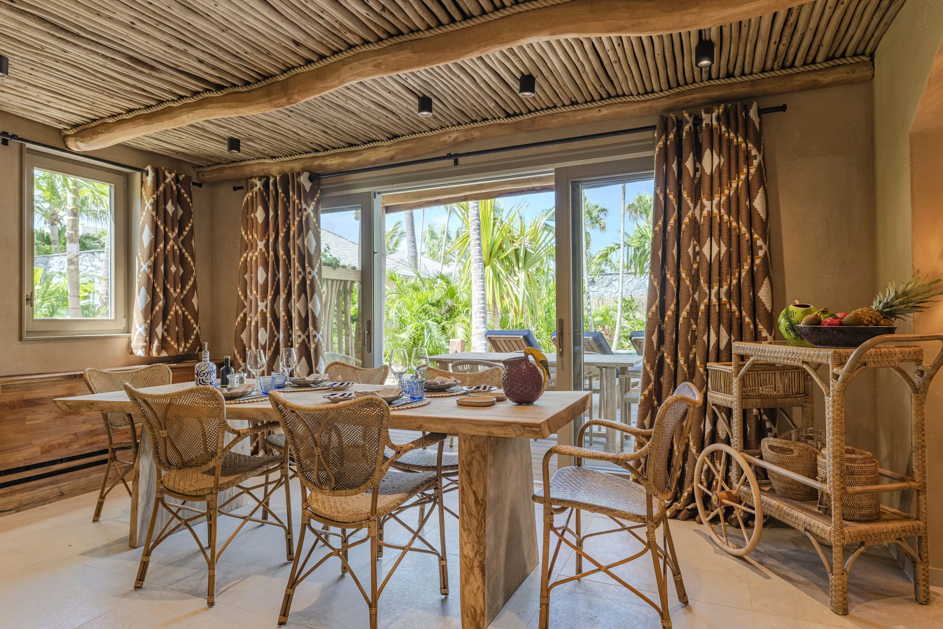 Dining area with rattan chairs and garden-facing glass doors at GYP SEA Saint Barth.