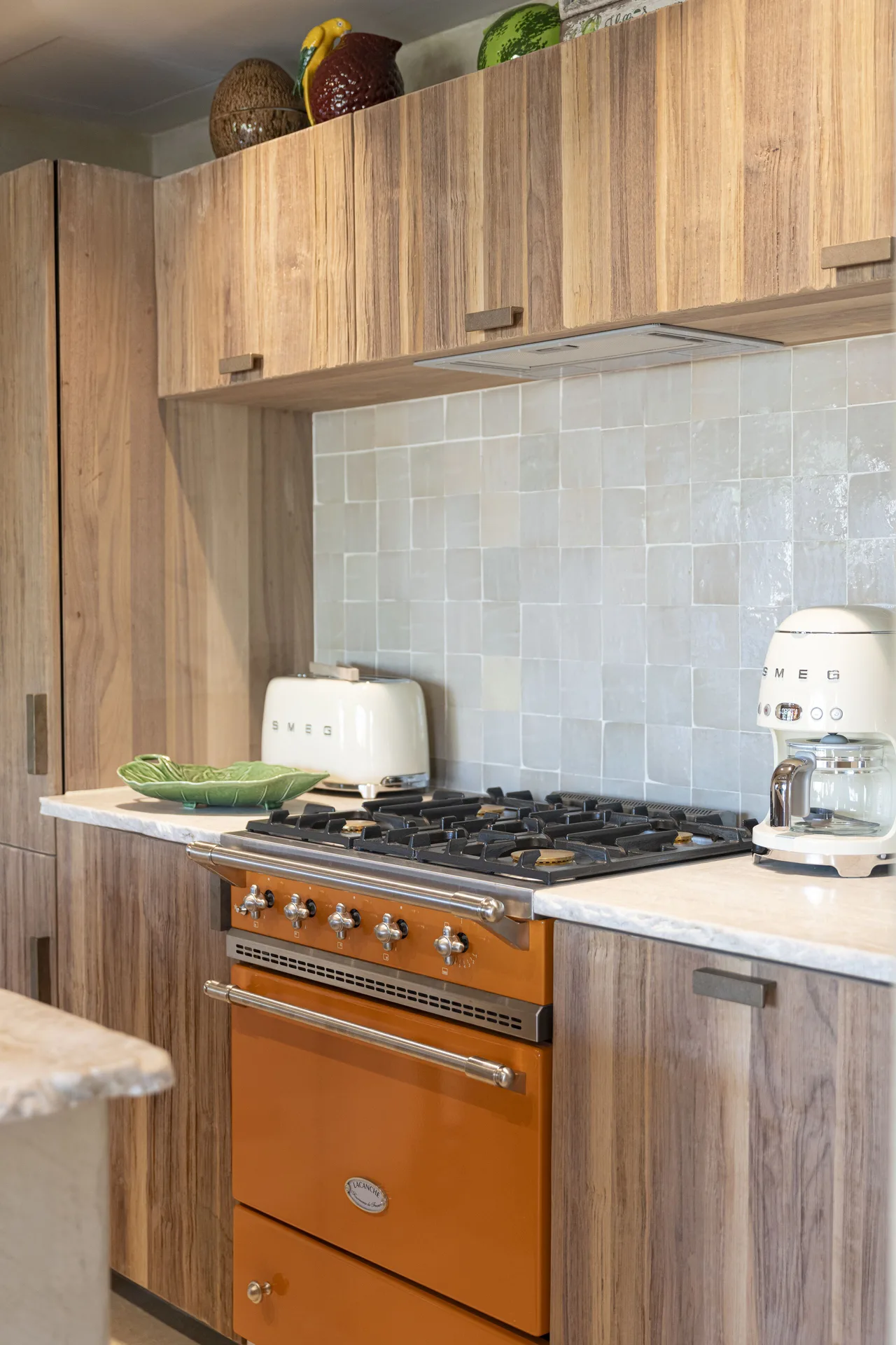 Kitchen with wood cabinets, tiled backsplash and orange range at GYP SEA Saint Barth.