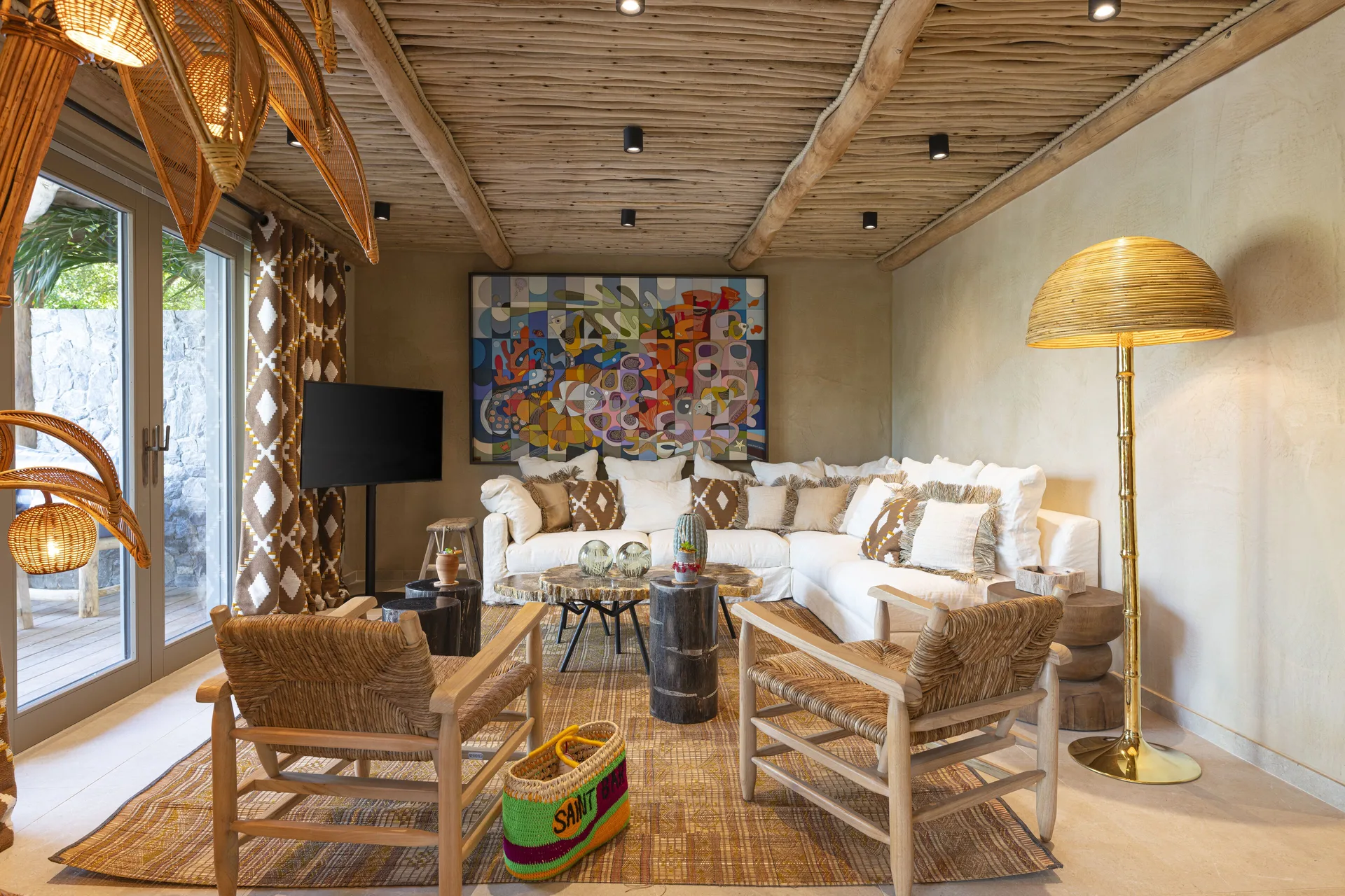 Living room with sectional sofa, woven chairs and art at GYP SEA Saint Barth.