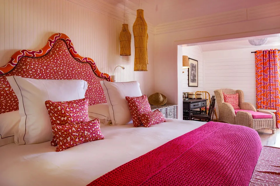 Family Suite king bed with bright pink accents at GYP SEA Saint Barth.