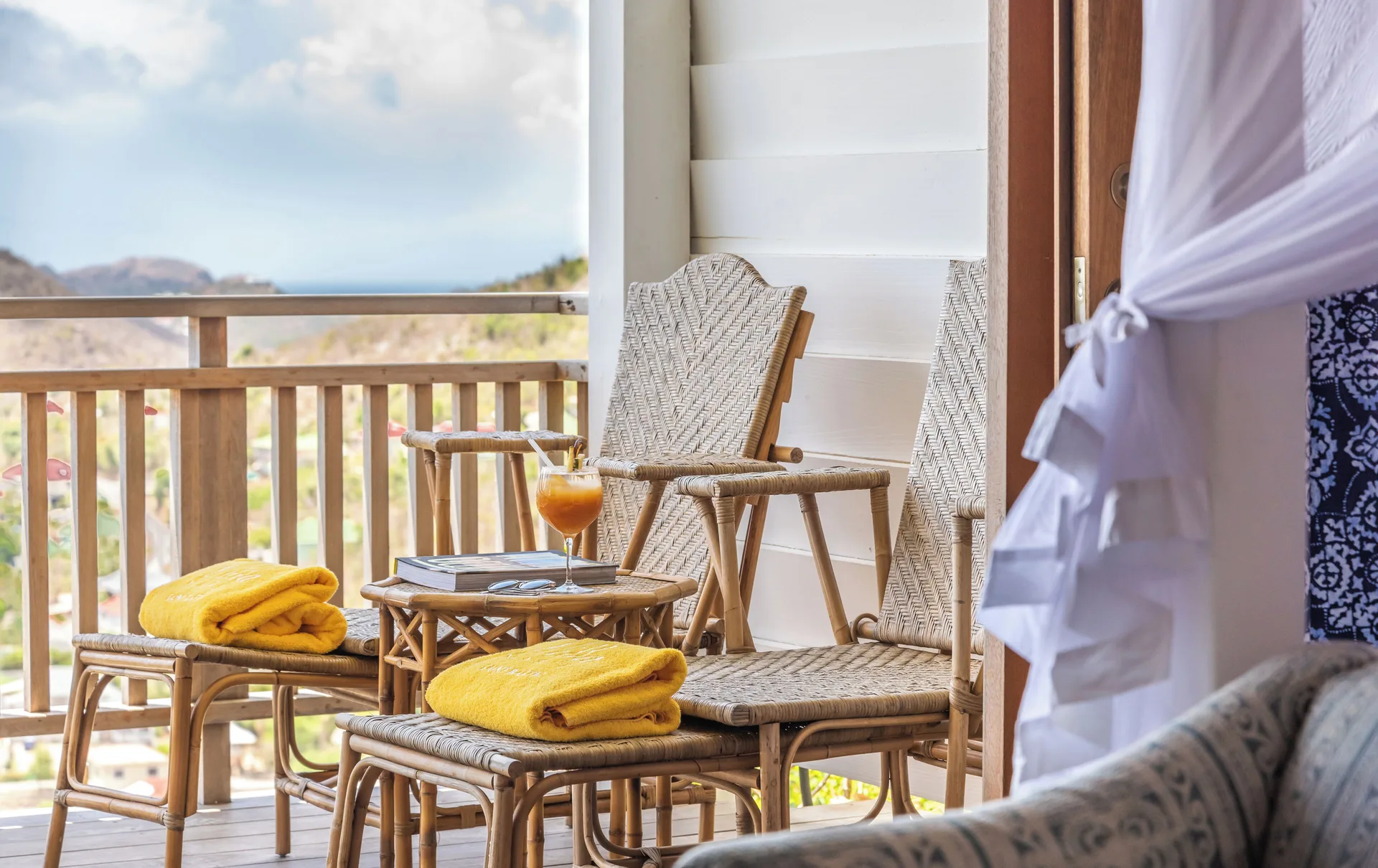 Havana Suite balcony chairs with yellow towels and a drink at GYP SEA Saint Barth.