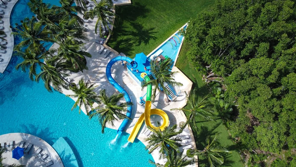 Aerial view of pools, waterslides, palms, and trees at Hacienda Tres Rios Resort, Spa & Nature Park.