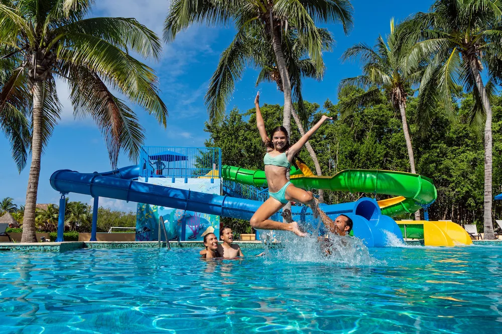 Family playing in a pool with colorful waterslides at Hacienda Tres Rios Resort, Spa & Nature Park.