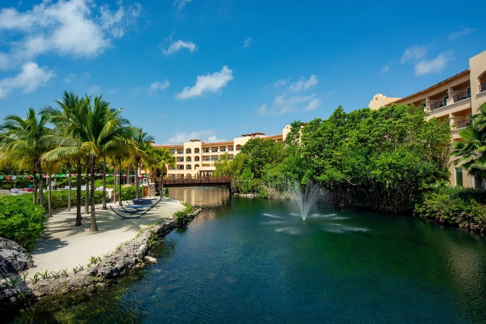 Lagoon, fountain, palms, and resort buildings at Hacienda Tres Rios Resort, Spa & Nature Park.