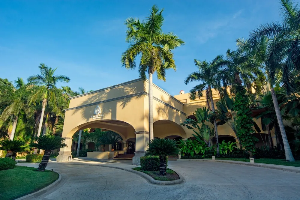 Palm-lined entrance and arched porte cochere at Hacienda Tres Rios Resort, Spa & Nature Park.