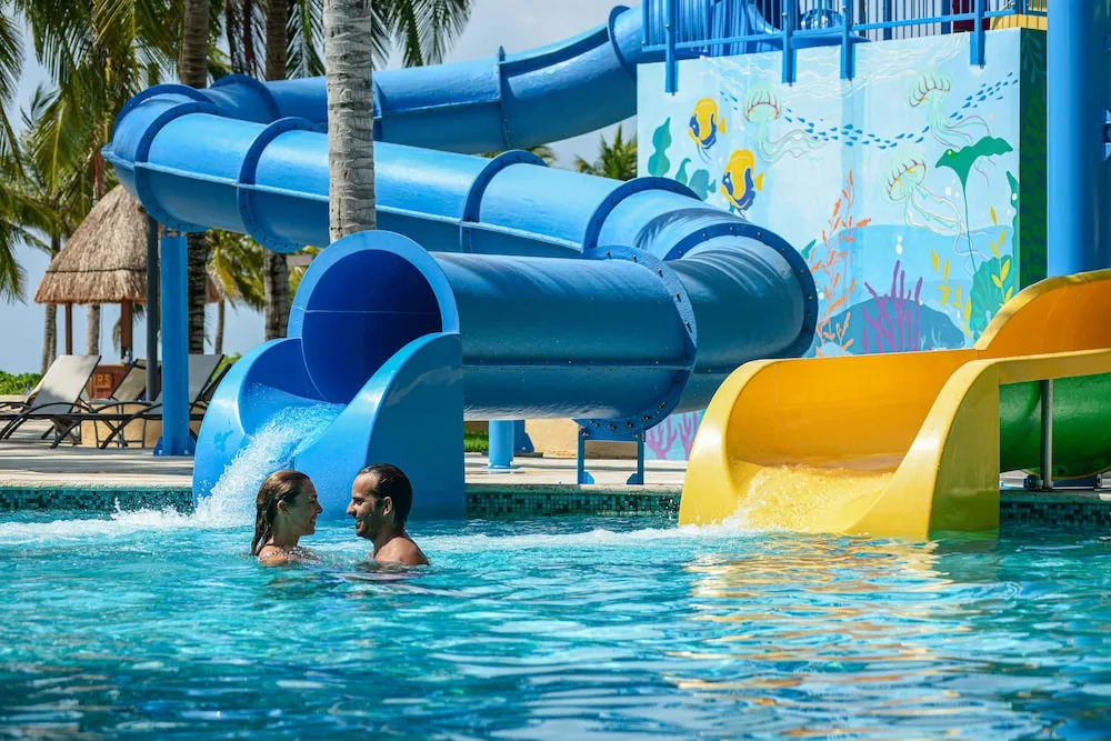 Blue and yellow pool slides with swimmers at Hacienda Tres Rios Resort, Spa & Nature Park.
