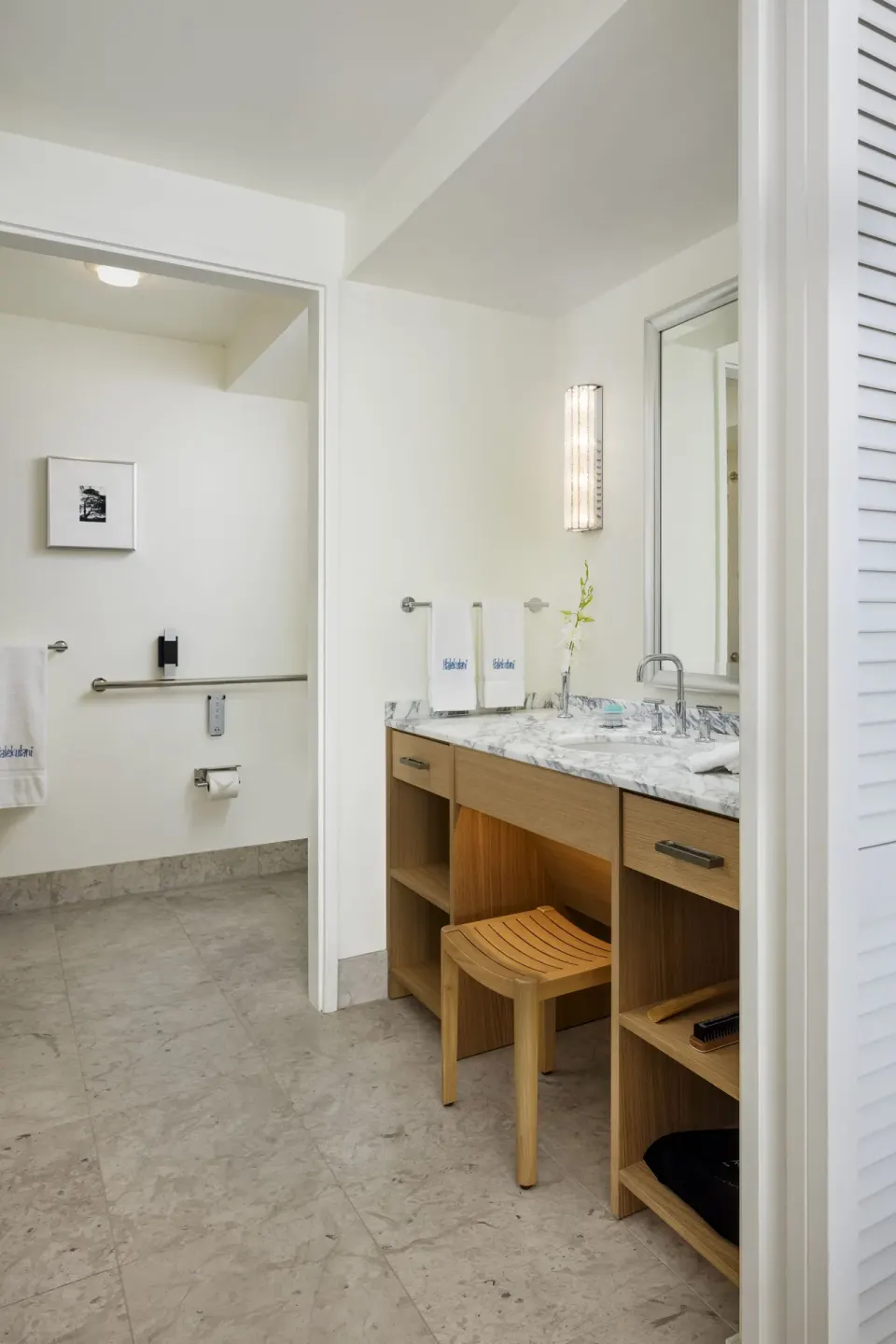 Bathroom vanity with marble counter, mirror, towels, and stool at Halekulani.