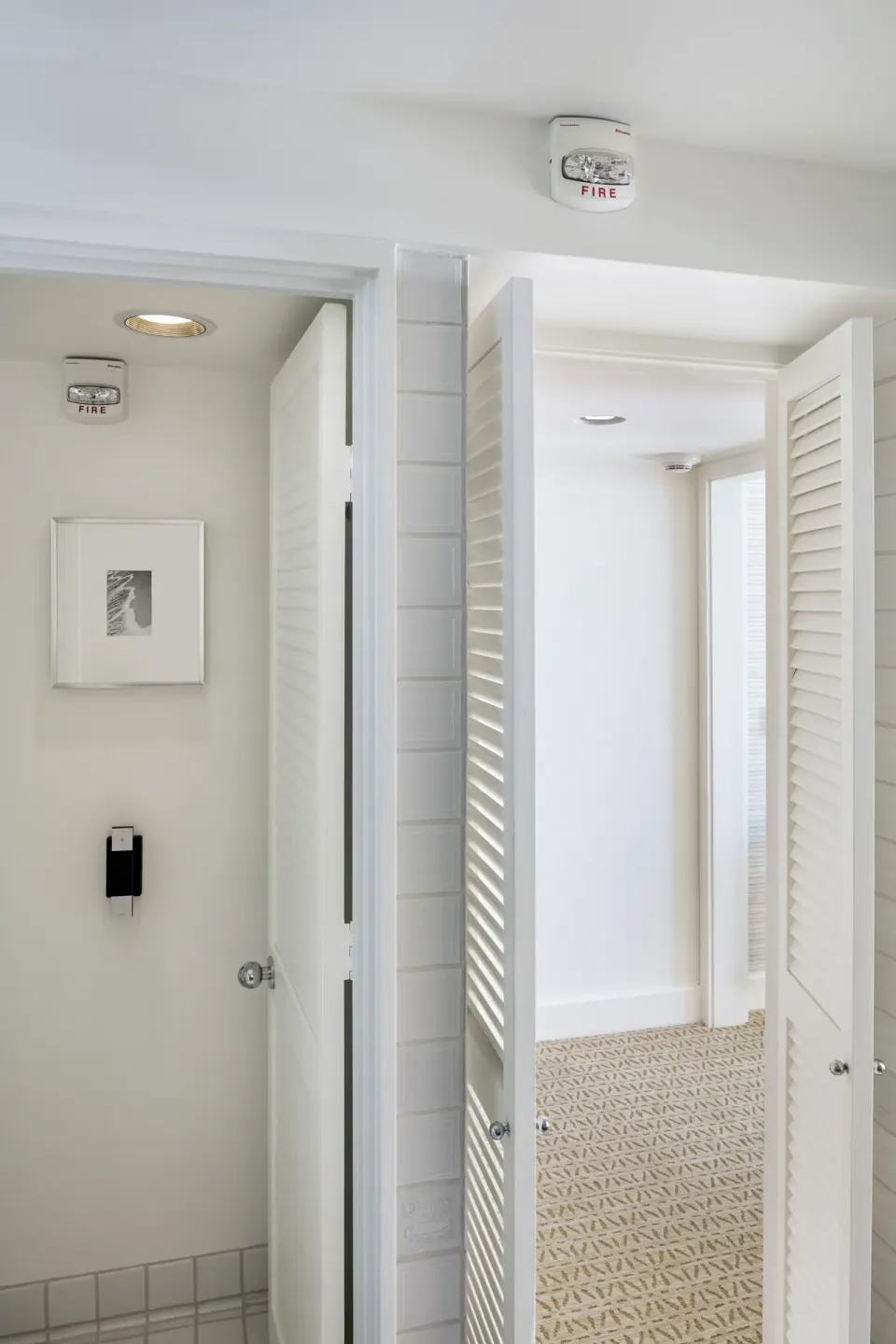 White guest room corridor with louvered doors and tiled entry at Halekulani.