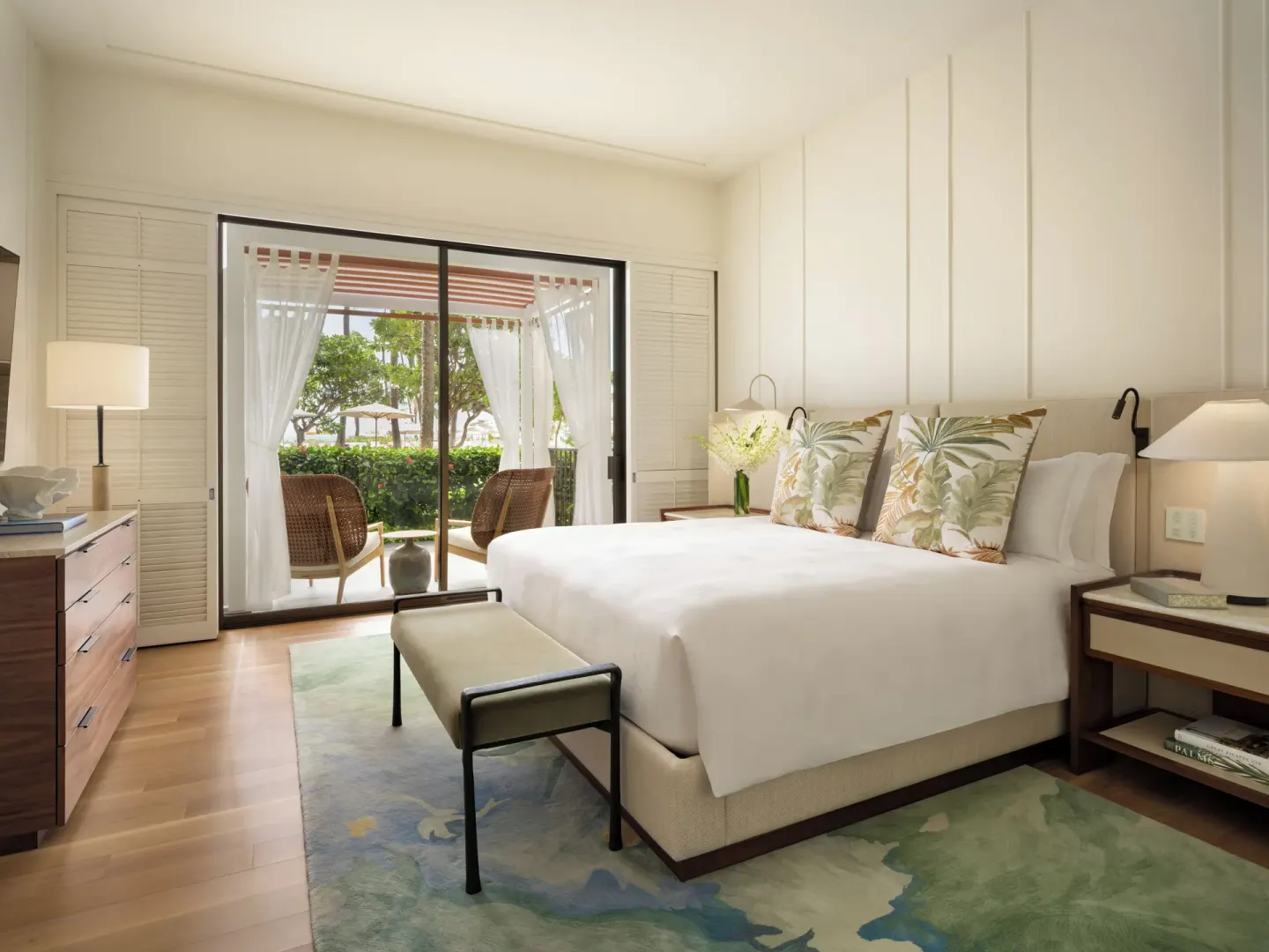 Guest room at Halekulani with a king bed, lanai seating, and garden beyond the doors.
