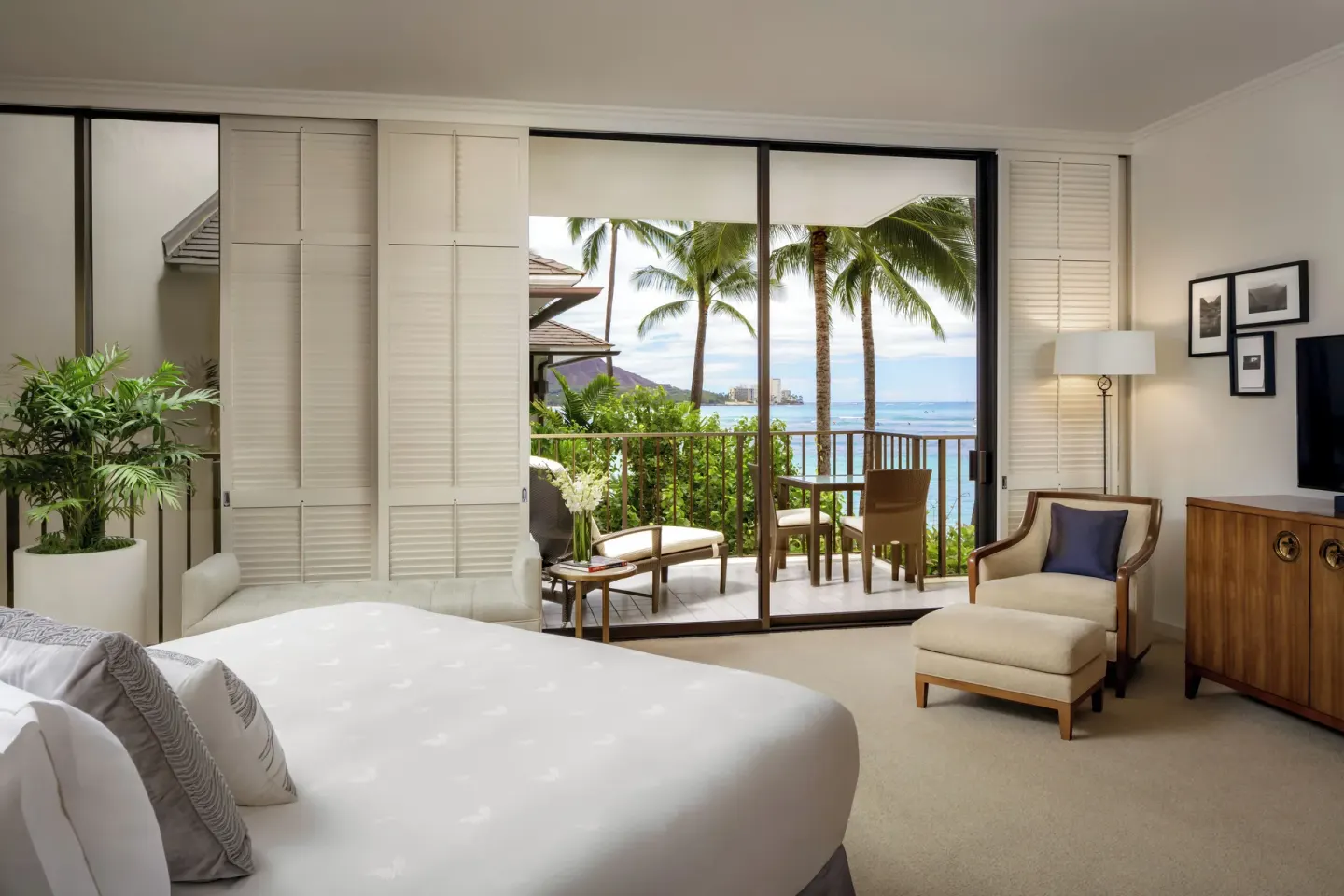 Guest room at Halekulani with a king bed, balcony seating, palms, and ocean view.