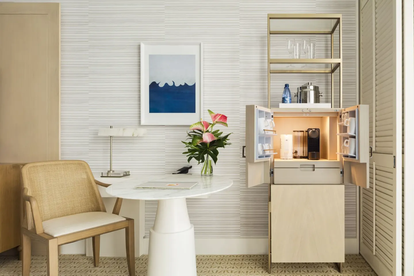 Guest room table, woven chair, flowers, and open refreshment cabinet at Halekulani.