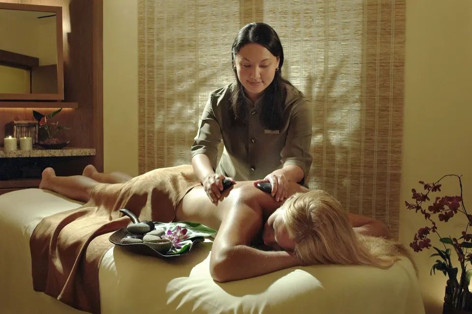 Hot stone massage treatment in a softly lit spa room at Halekulani.