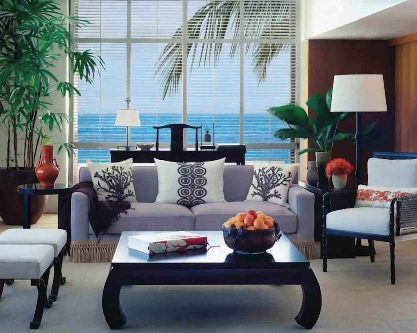 Ocean-facing living room with sofa, coffee table, plants, and shuttered windows at Halekulani.