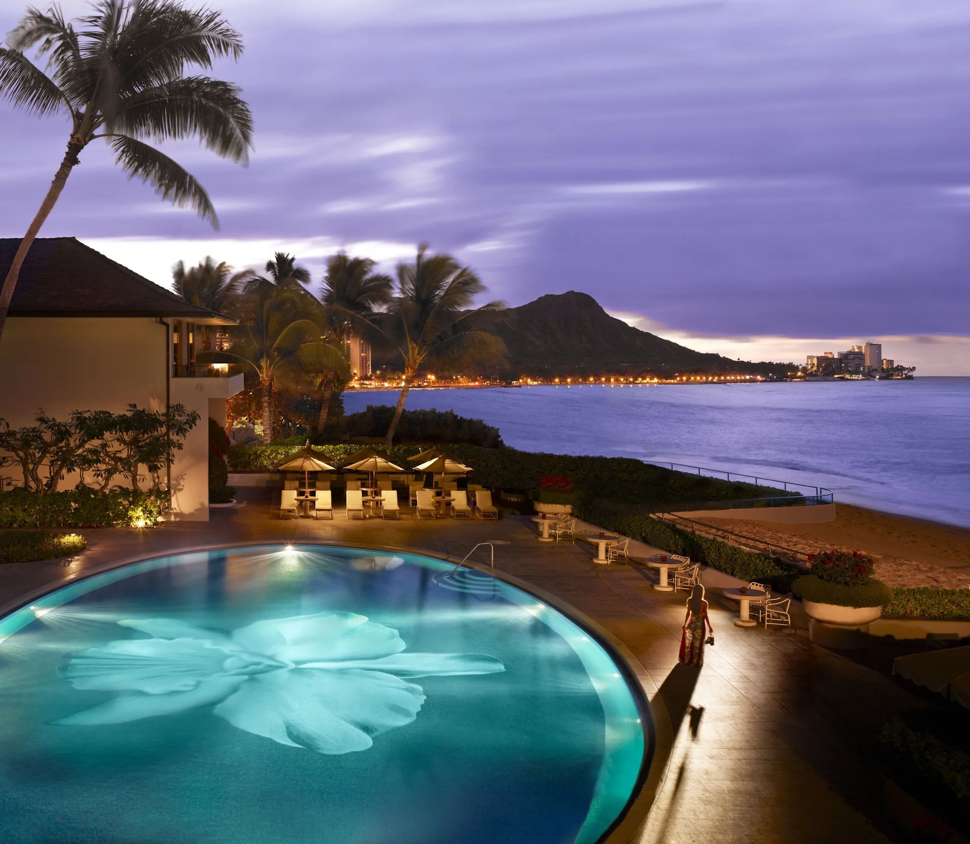 Pool and beach at dusk with Diamond Head beyond Halekulani.