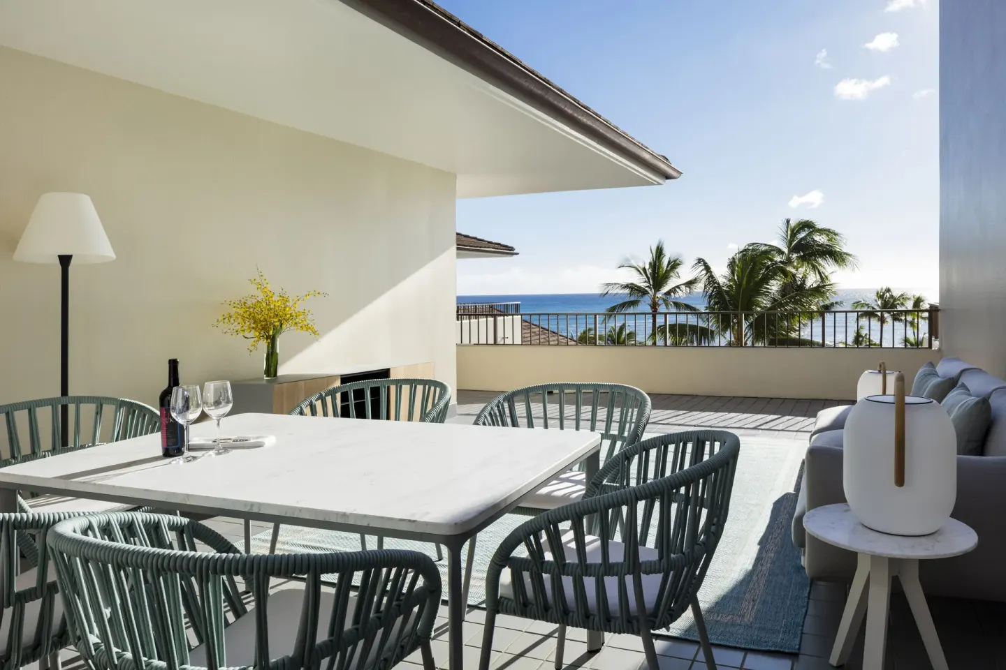 Private terrace with dining table, lounge seating, palms, and ocean view at Halekulani.