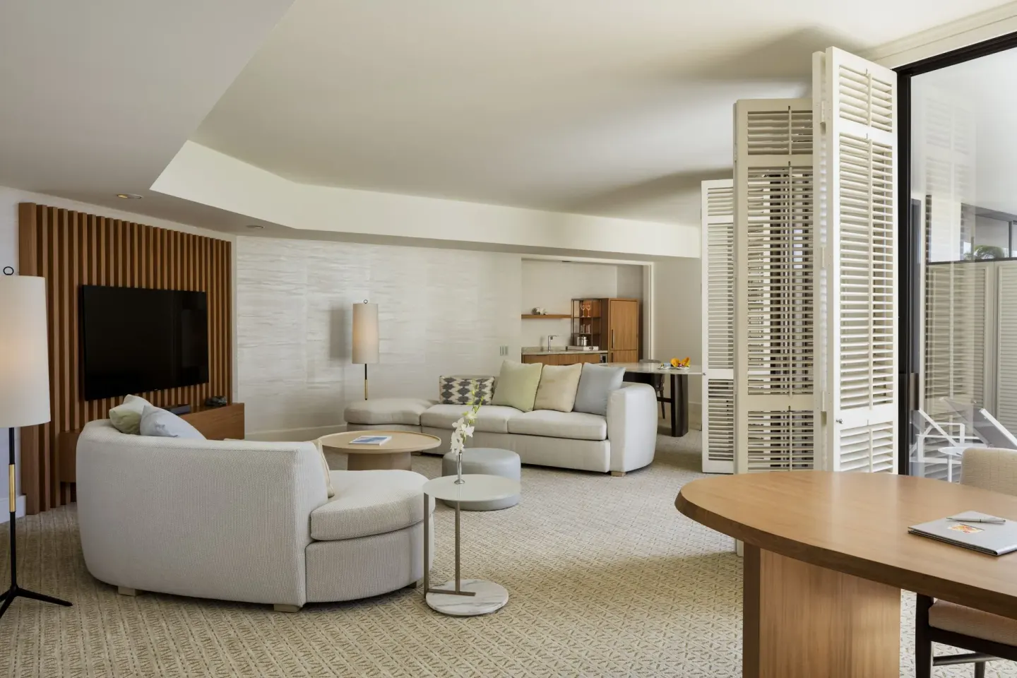 Spacious suite living area with sofas, TV wall, dining table, and balcony at Halekulani.