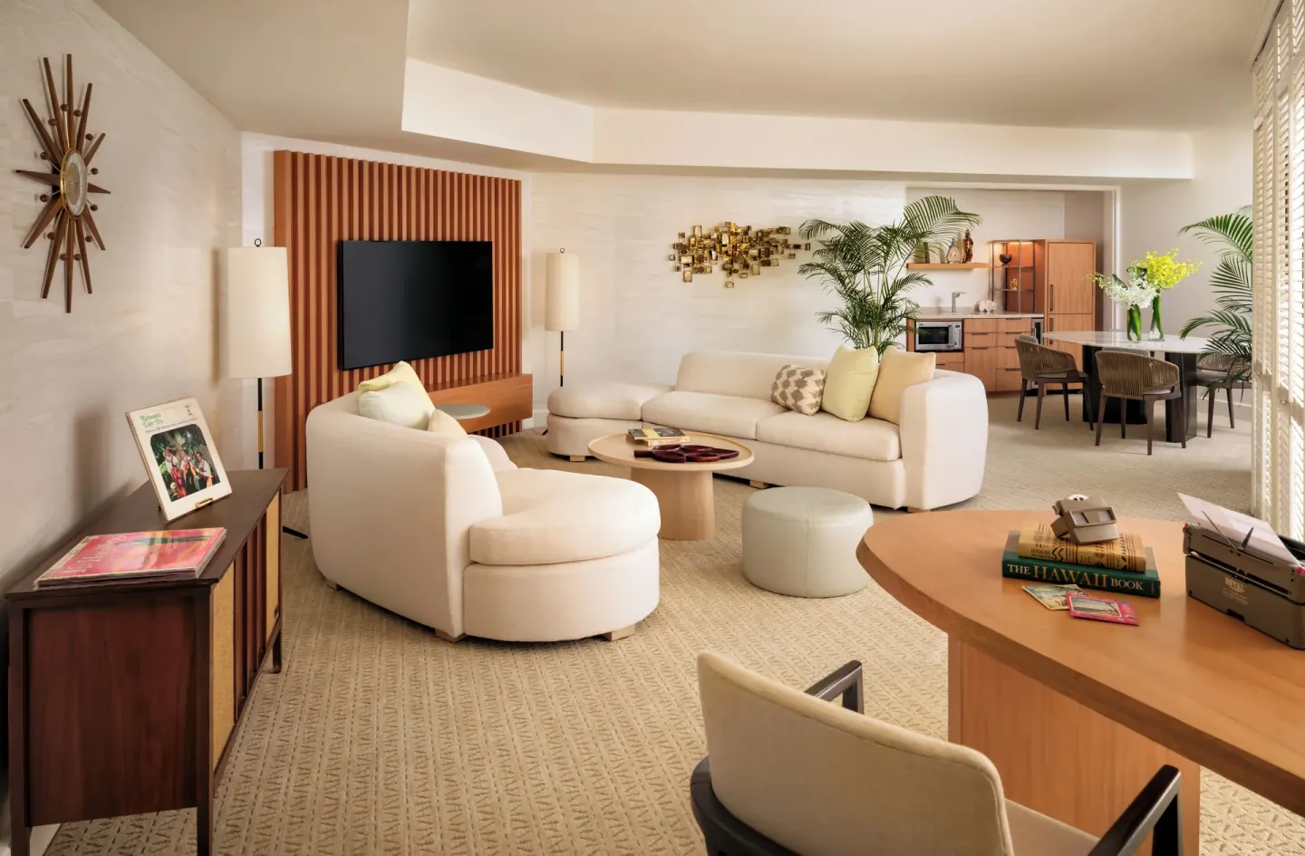 Suite living area with white seating, desk, dining table, and kitchenette at Halekulani.