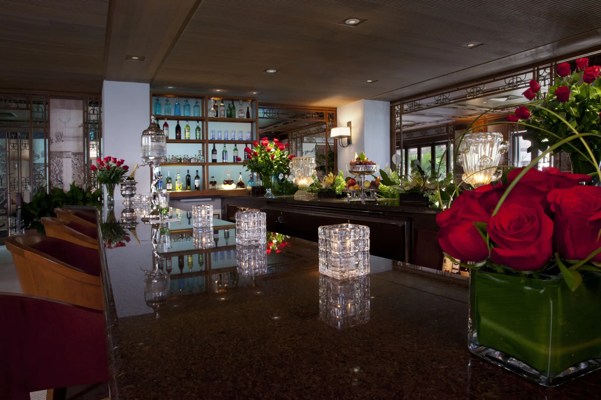 A polished lounge bar with red roses and candlelight is shown inside Halekulani.