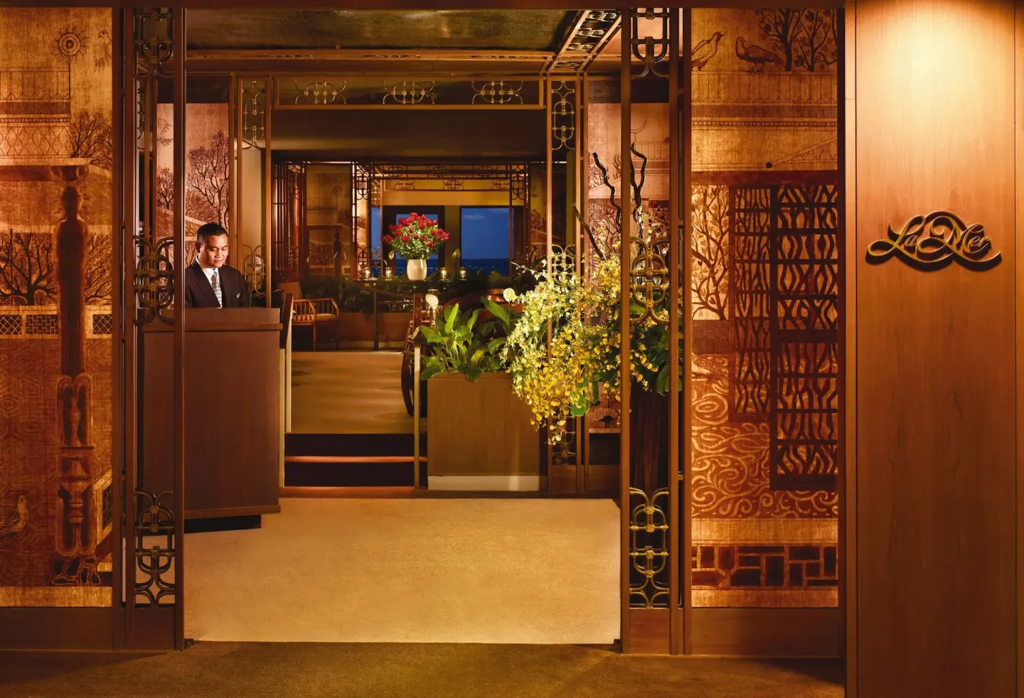The La Mer entrance with a host stand and decorative panels is shown at Halekulani.