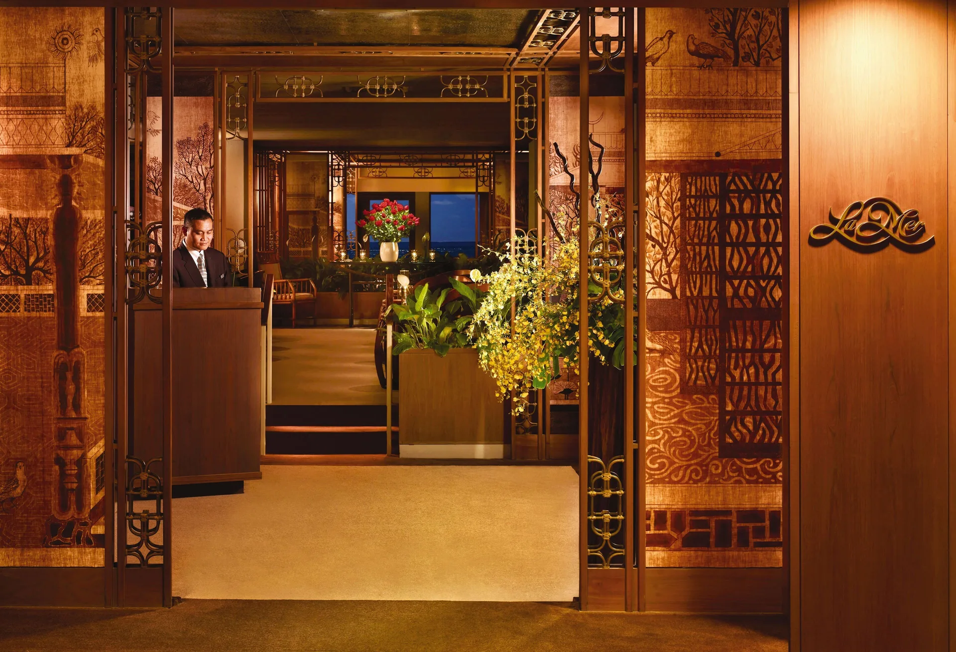 The La Mer entrance with a host stand and decorative panels is shown at Halekulani.