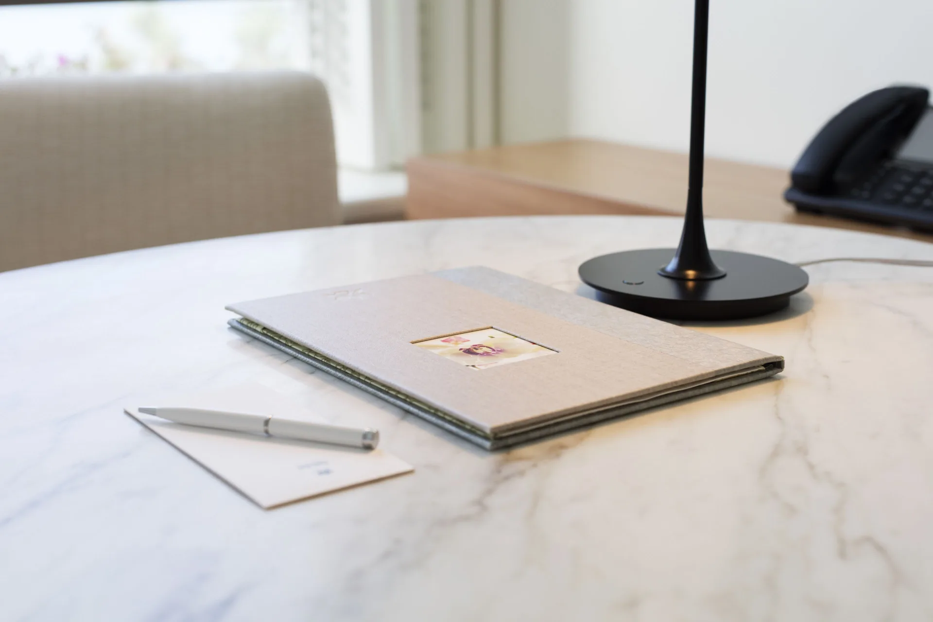 Writing folder, pen, lamp and phone on a marble desk in a Junior Suite at Halekulani.