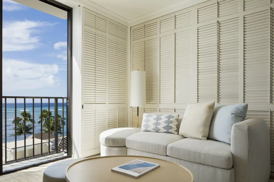 Ocean-view sitting area with sofa and balcony doors in a Junior Suite at Halekulani.