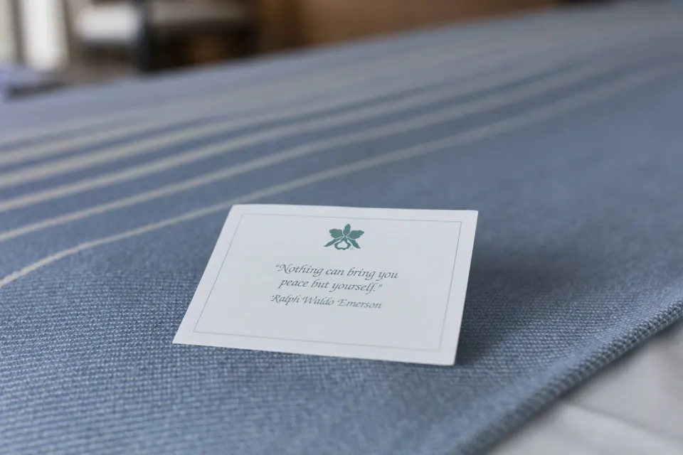 Quote card resting on a blue bed runner in a Halekulani guest room.