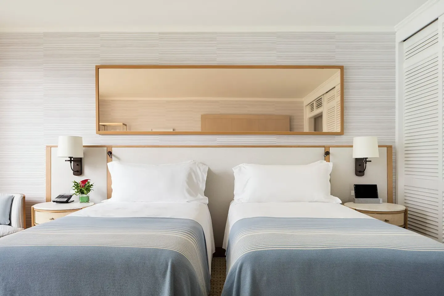 Garden Courtyard room with twin beds, bedside lamps and mirror at Halekulani.