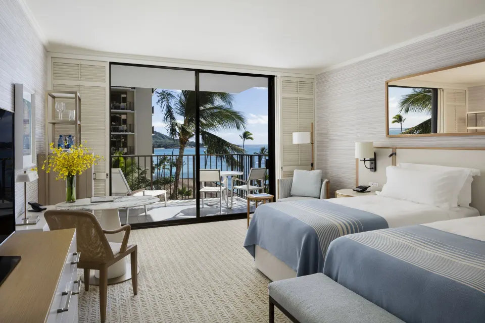 Ocean View room with two beds, balcony seating, palms, and ocean beyond at Halekulani.