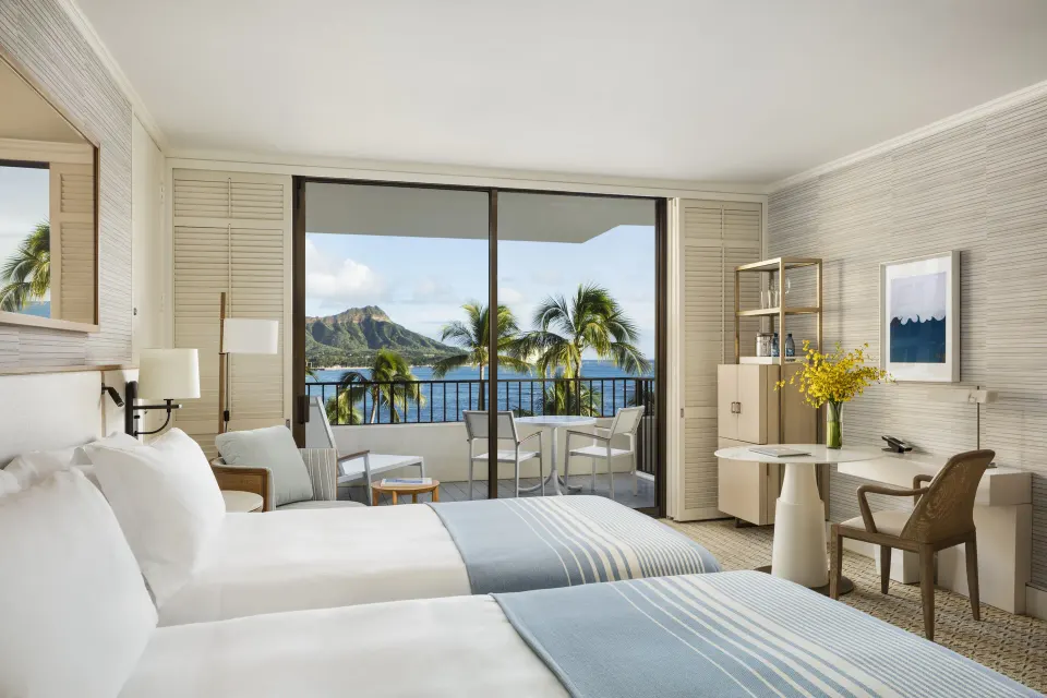 Oceanfront Diamond Head room at Halekulani with two beds, desk, balcony, palms, and ocean view.