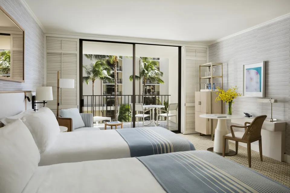 Two-bed Partial Ocean View room at Halekulani with balcony seating, desk, and palm views.