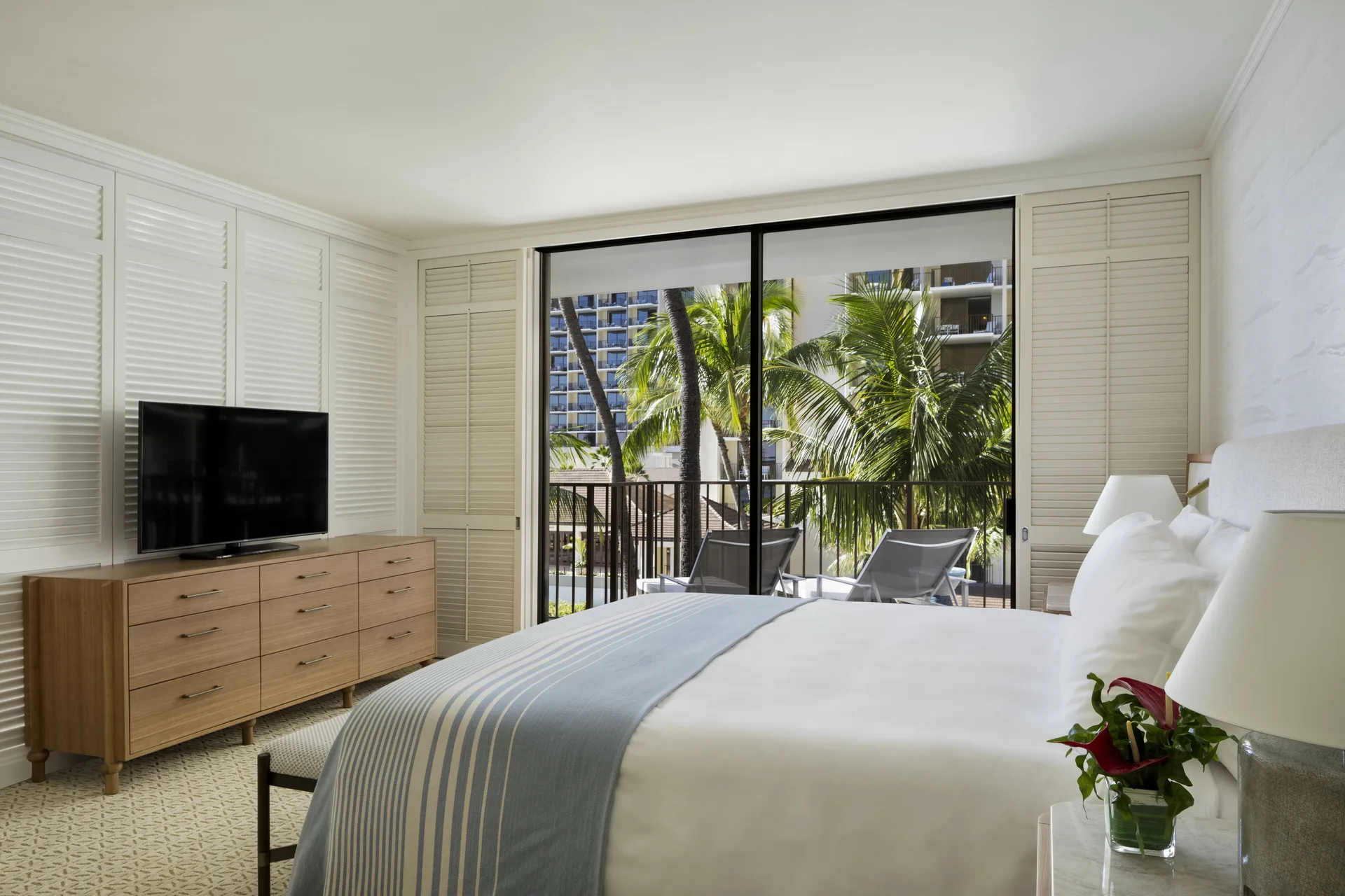 Suite Pool View bedroom with king bed, balcony, palms and television at Halekulani.