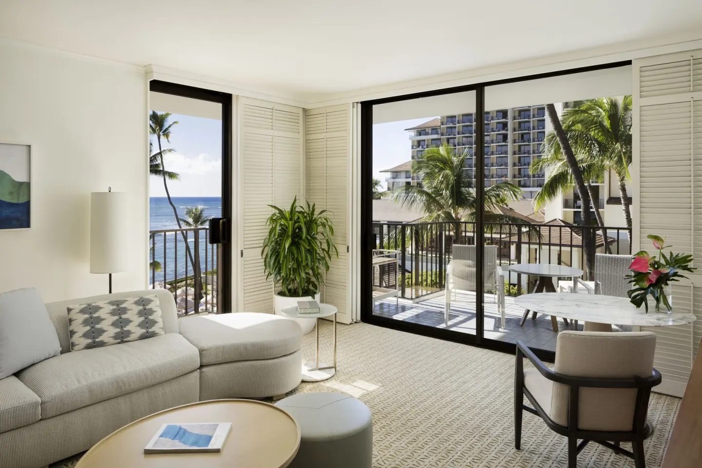 Suite living room with ocean-view lanai and palm trees at Halekulani.