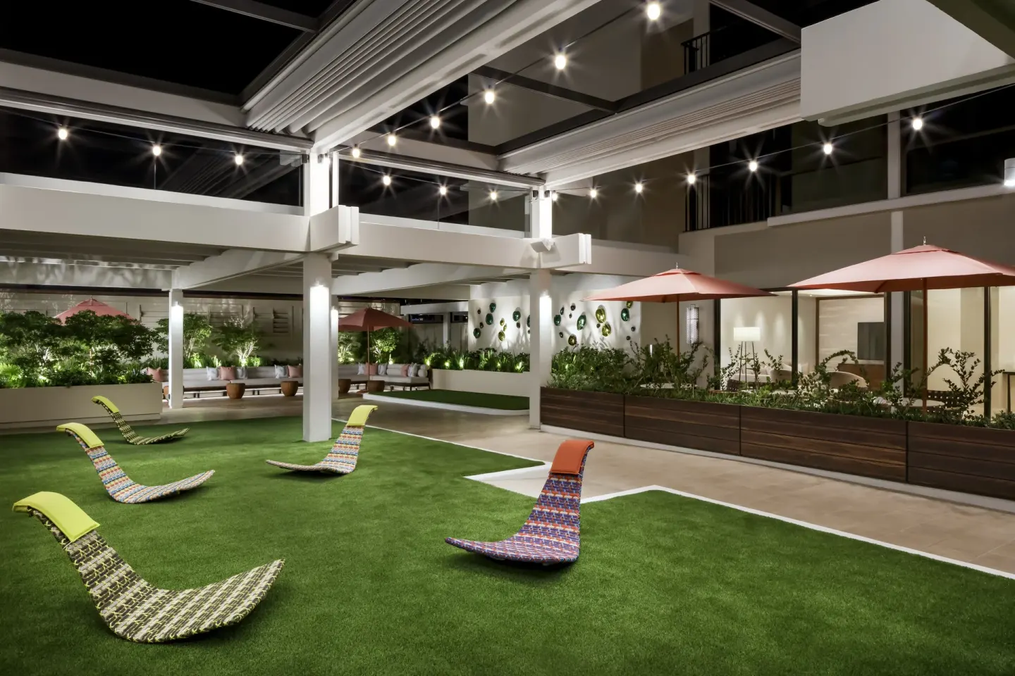 Nighttime courtyard lawn with woven lounge chairs at Halepuna Waikiki by Halekulani.