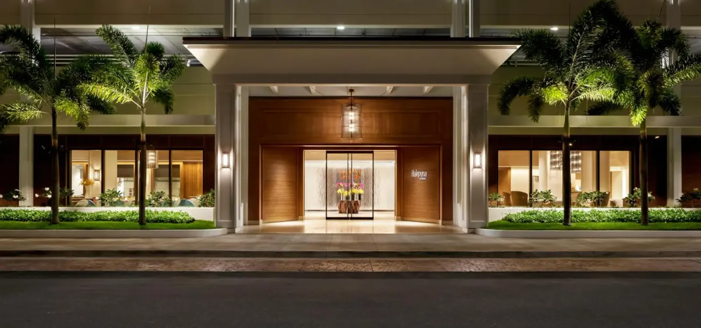 Illuminated front entrance and palms at Halepuna Waikiki by Halekulani.
