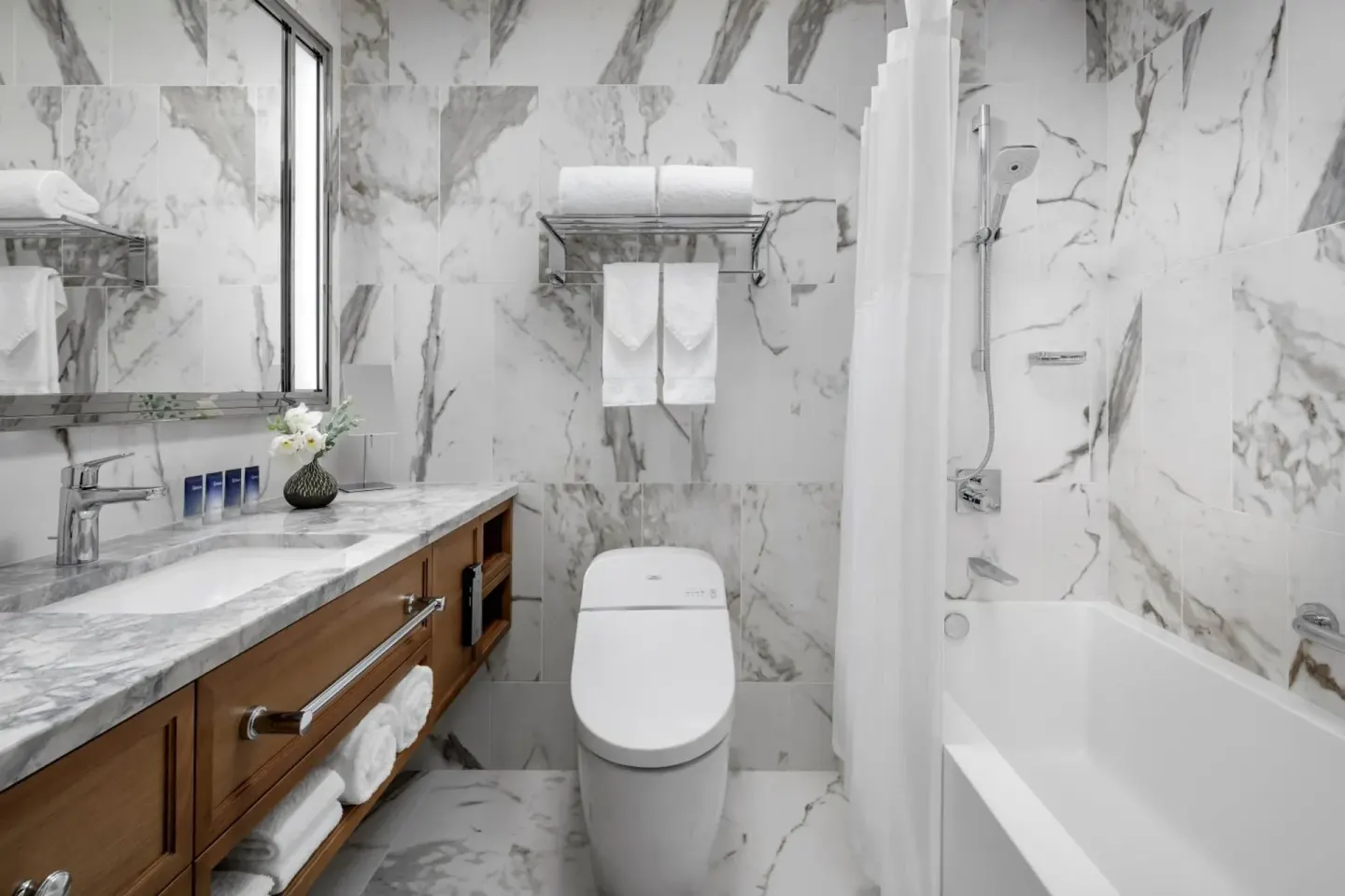Marble bathroom with vanity, toilet, and tub-shower at Halepuna Waikiki by Halekulani.