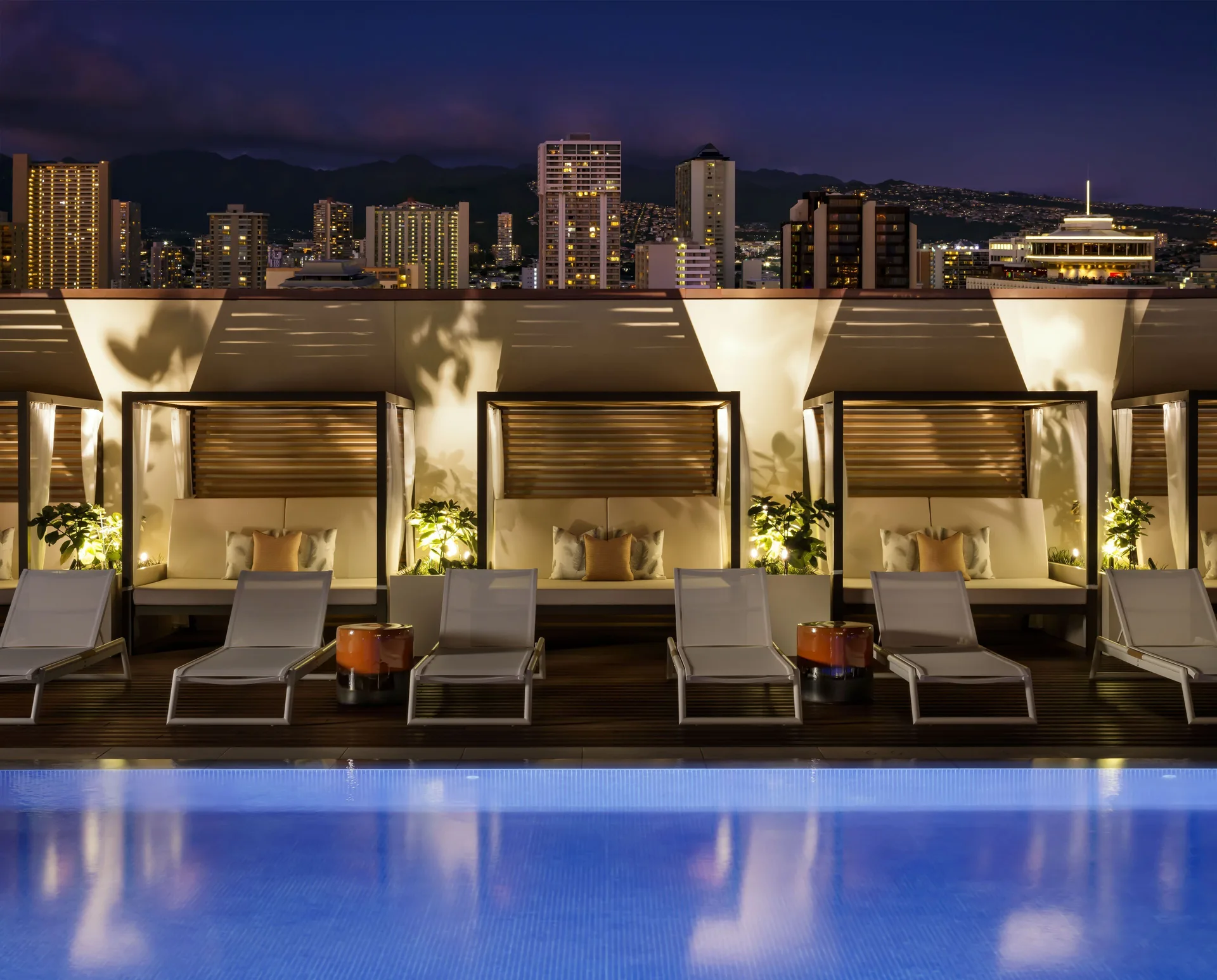 Nighttime poolside cabanas and lounge chairs at Halepuna Waikiki by Halekulani.