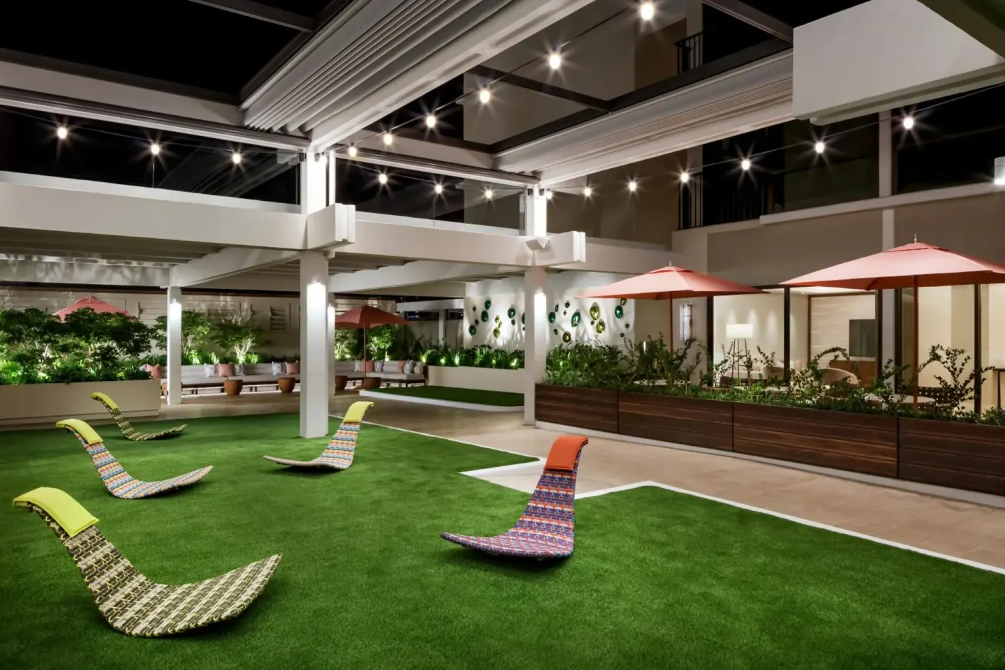 Open-air lawn terrace with chaise lounges at night at Halepuna Waikiki by Halekulani.