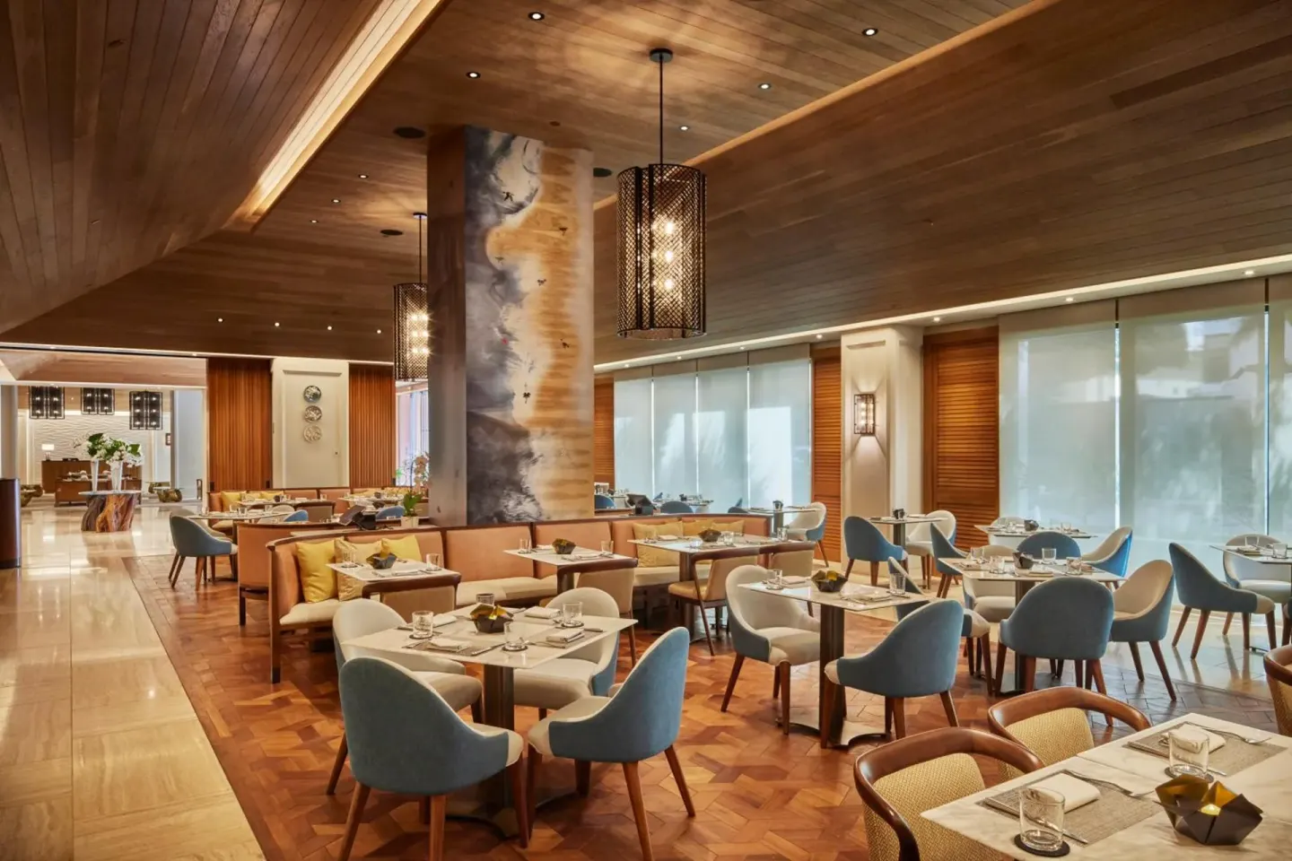 Dining room with set tables and blue chairs at Halepuna Waikiki by Halekulani.