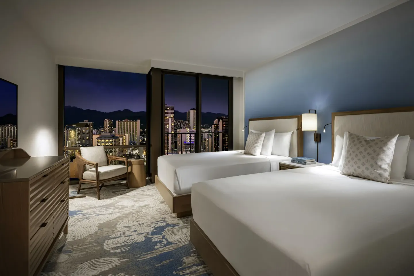 Standard Waikiki View room with two beds and nighttime city view at Halepuna Waikiki by Halekulani.