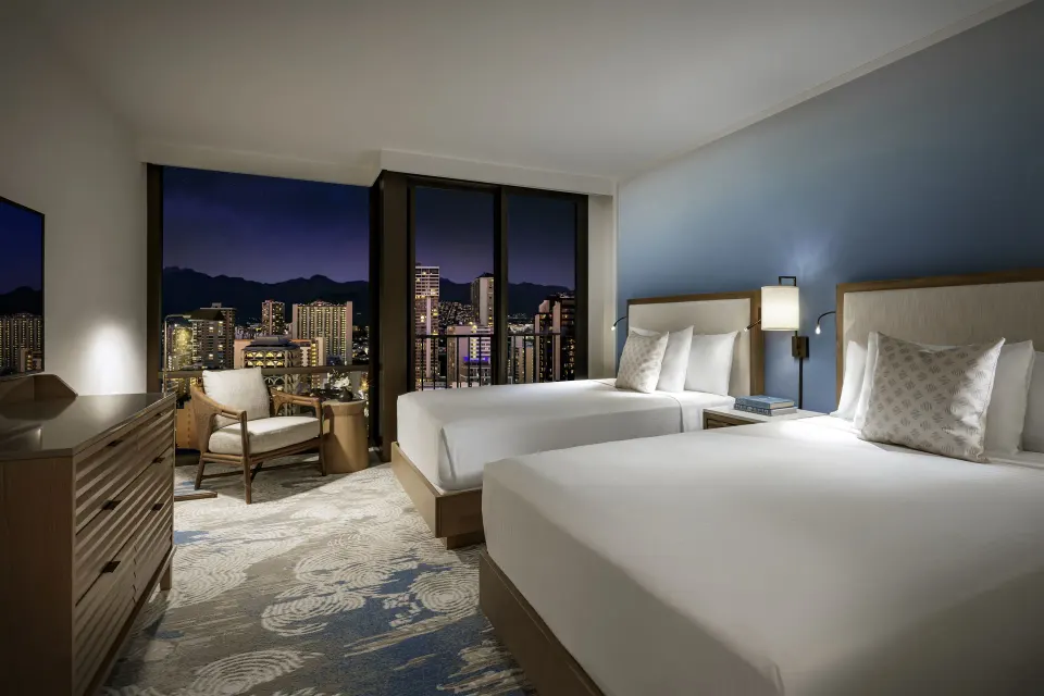 Standard Waikiki View room with two beds and nighttime city view at Halepuna Waikiki by Halekulani.