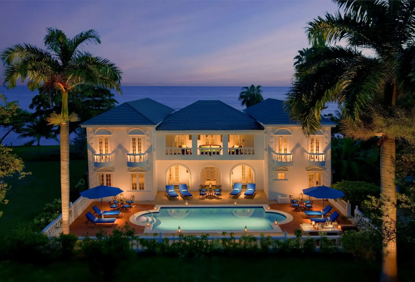 Illuminated oceanfront villa with pool at dusk at Half Moon.
