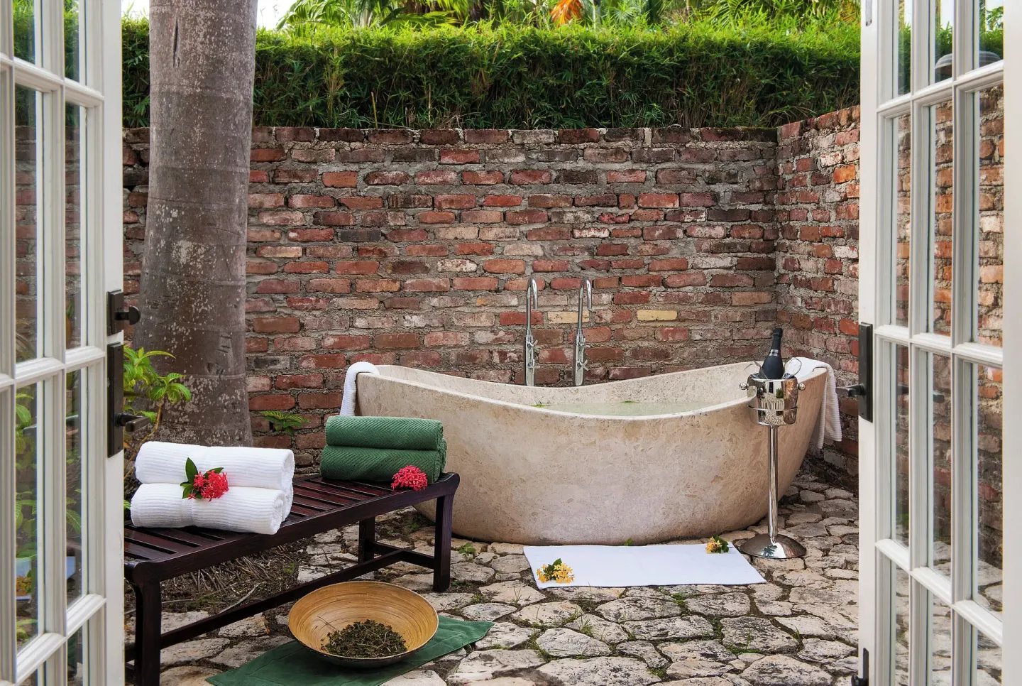 Open-air stone bathtub with towels and garden walls at Half Moon.