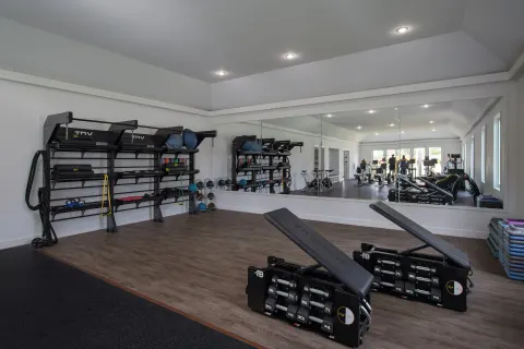 Weight benches and training equipment line a mirrored gym room at Half Moon.