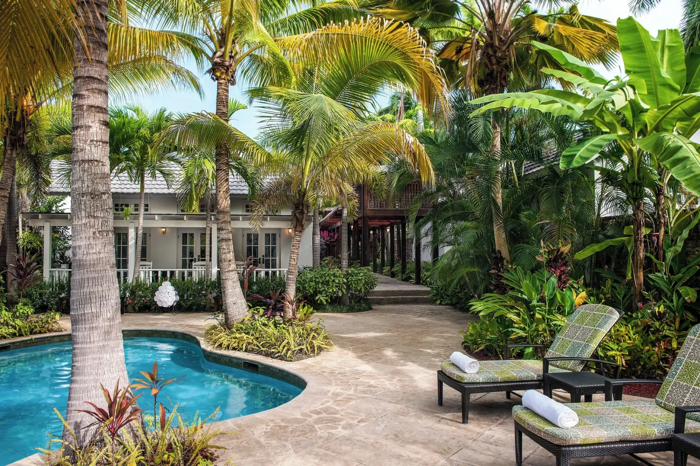 A palm-shaded pool courtyard with loungers sits among guest buildings at Half Moon.