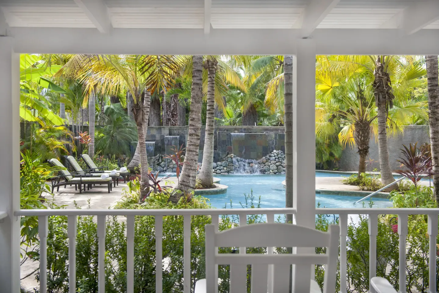 A covered veranda overlooks a palm-lined pool and waterfall at Half Moon.