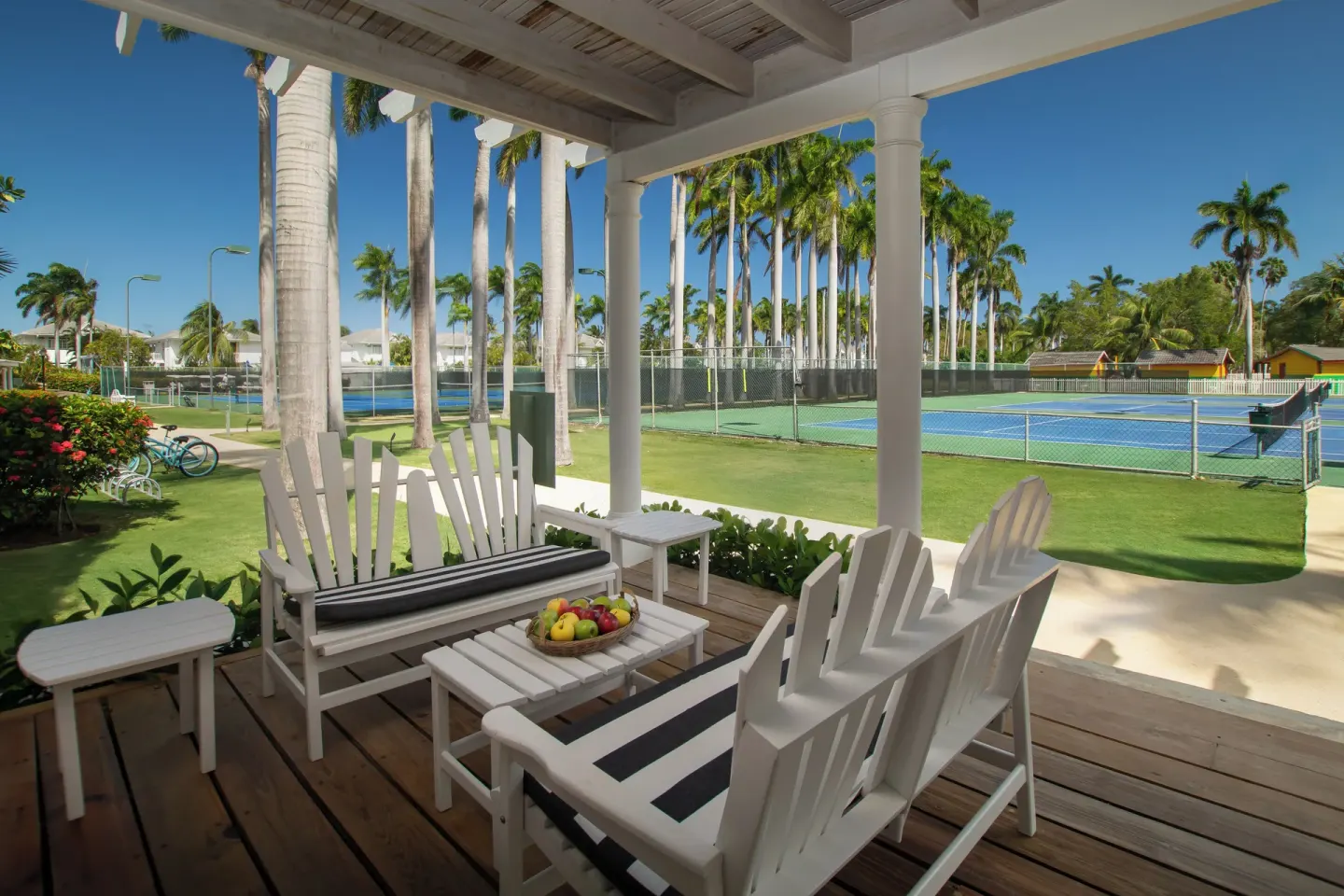 Shaded veranda seating overlooking tennis courts and palm lawns at Half Moon.
