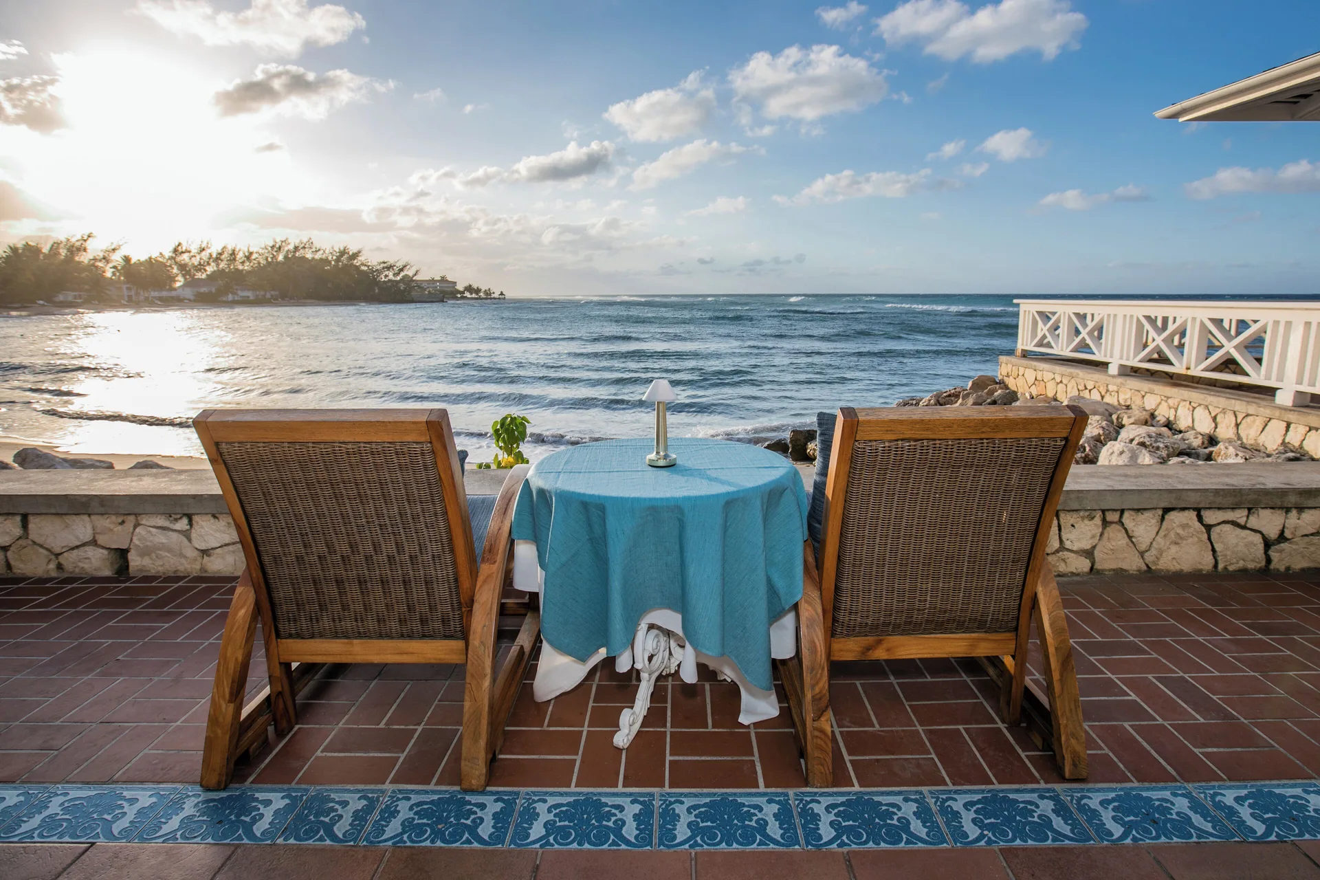 Oceanfront terrace table for two at Half Moon with wicker chairs and a sunset sea view.