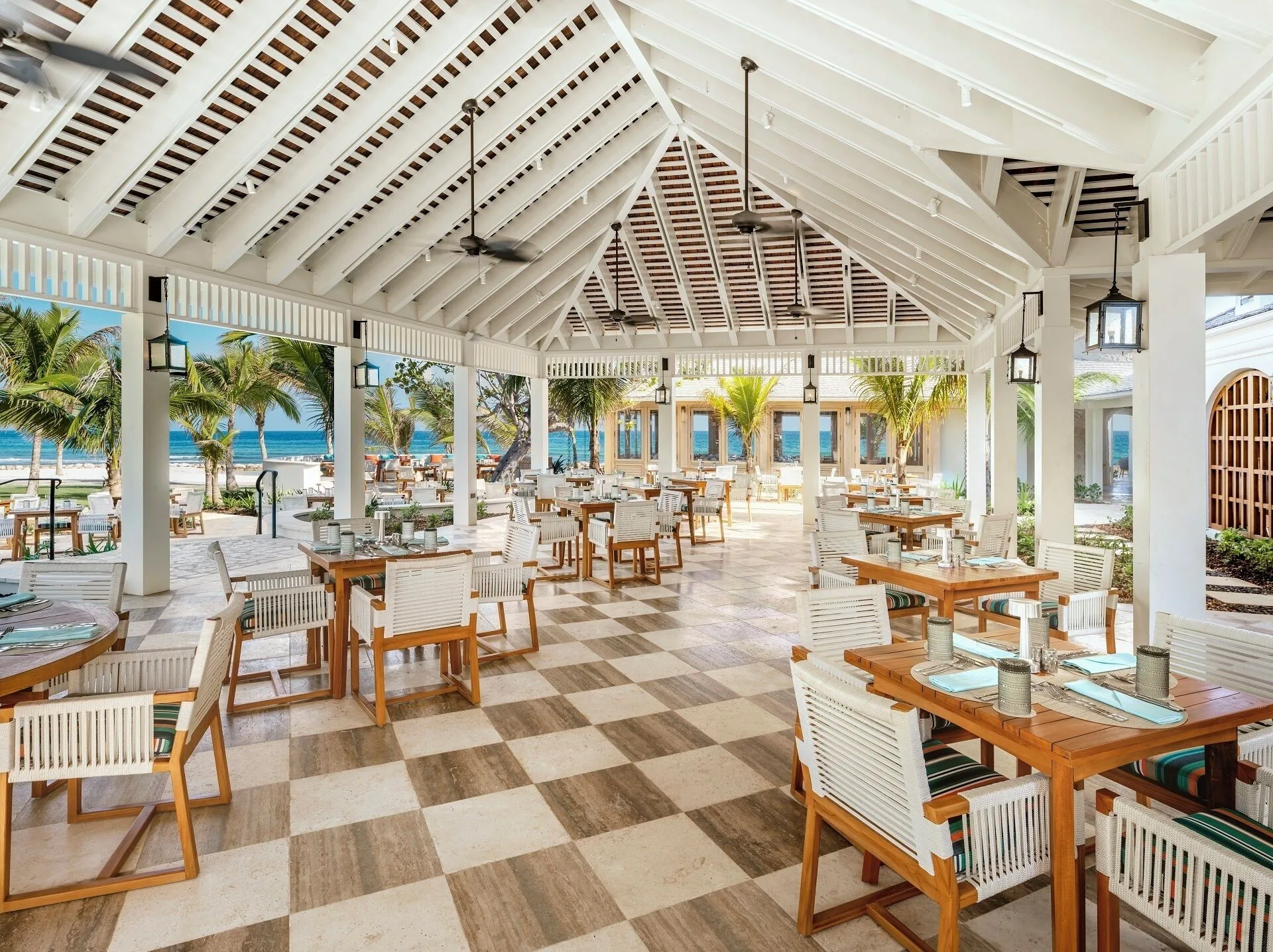 An open-air seaside dining terrace with set tables at Half Moon.